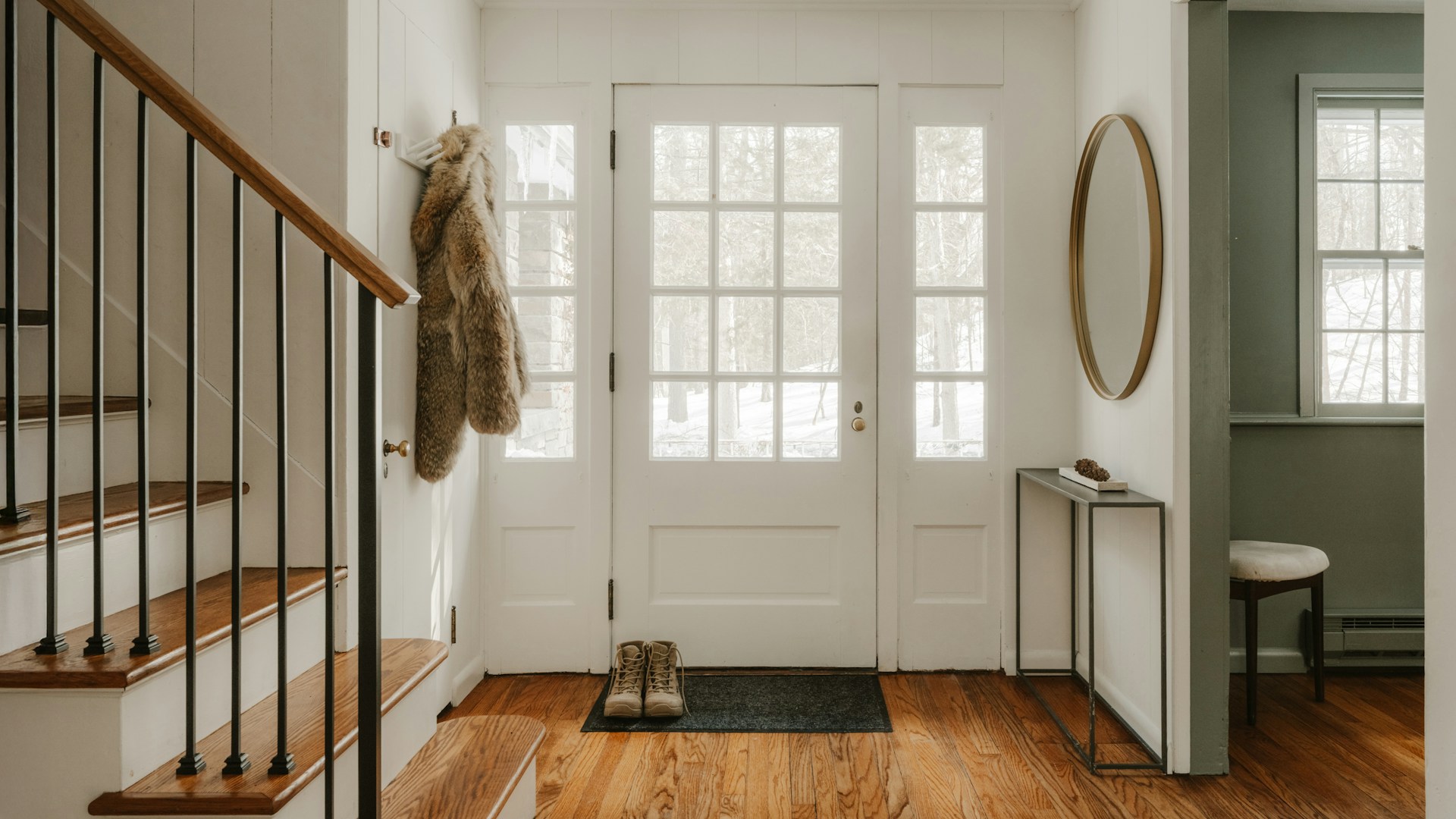 A cozy entryway with wooden stairs and a glass door.