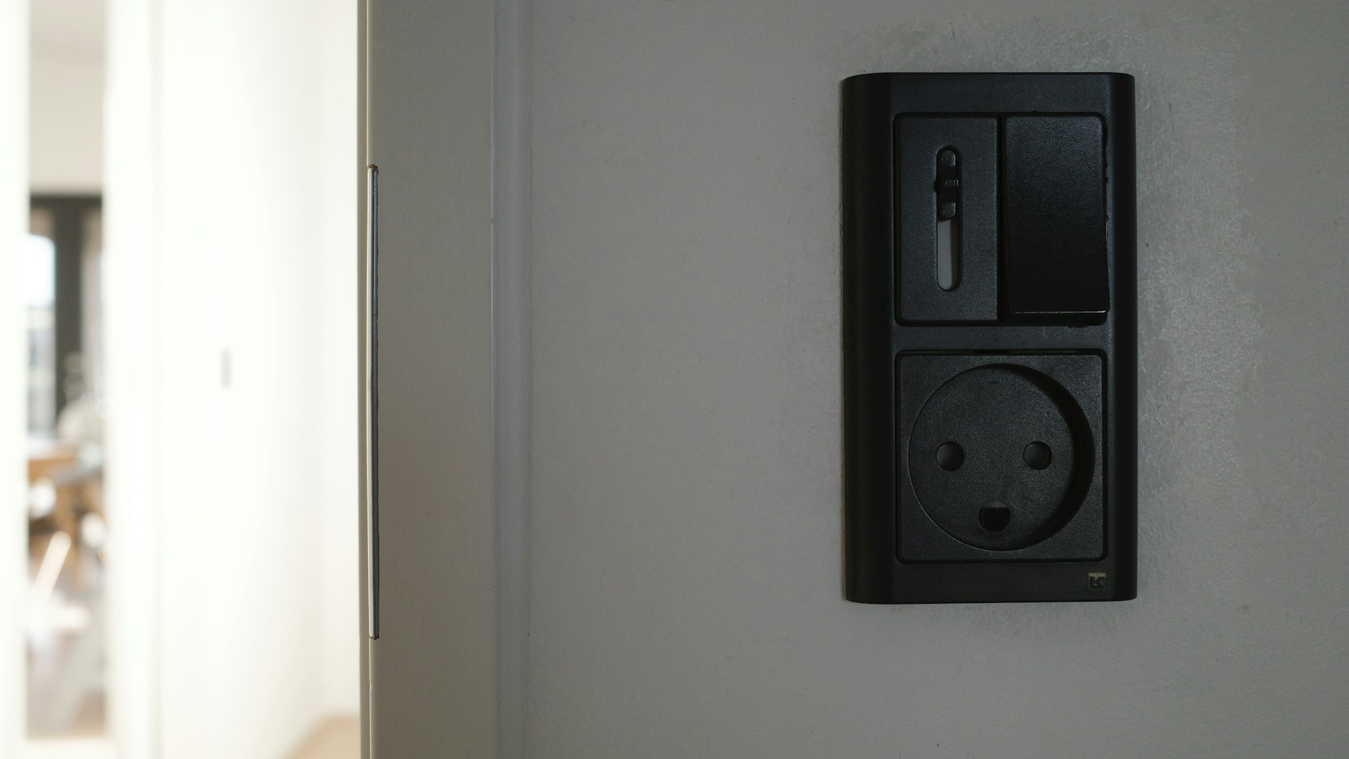 A black electrical outlet and switch on a wall.