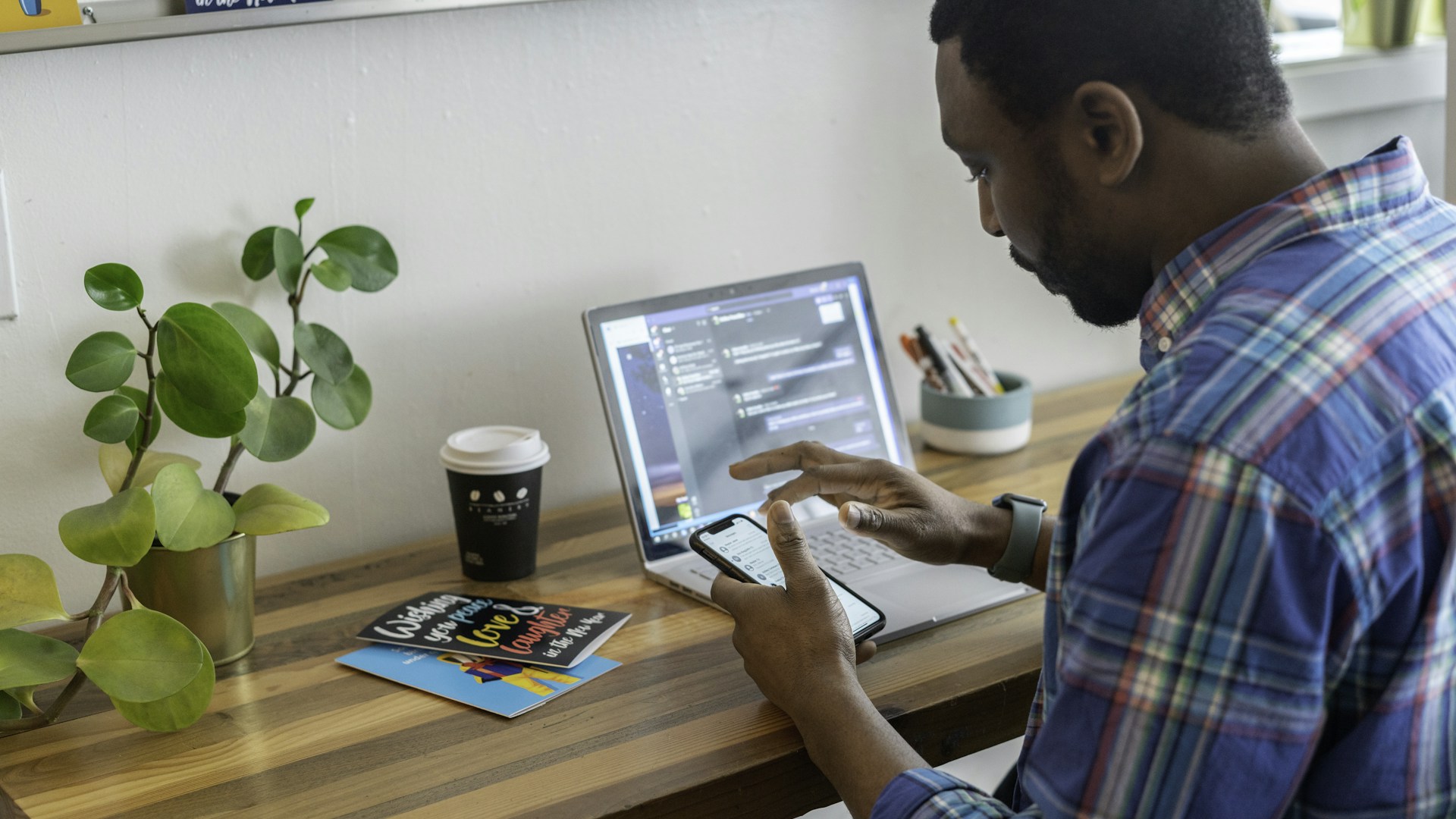 man in blue and red plaid dress shirt using silver ipad