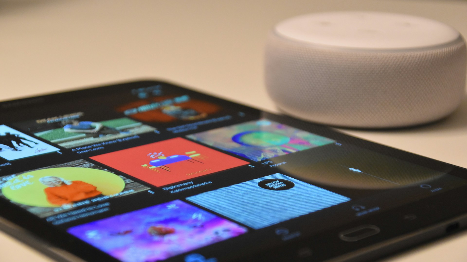 black tablet computer beside round white portable speaker
