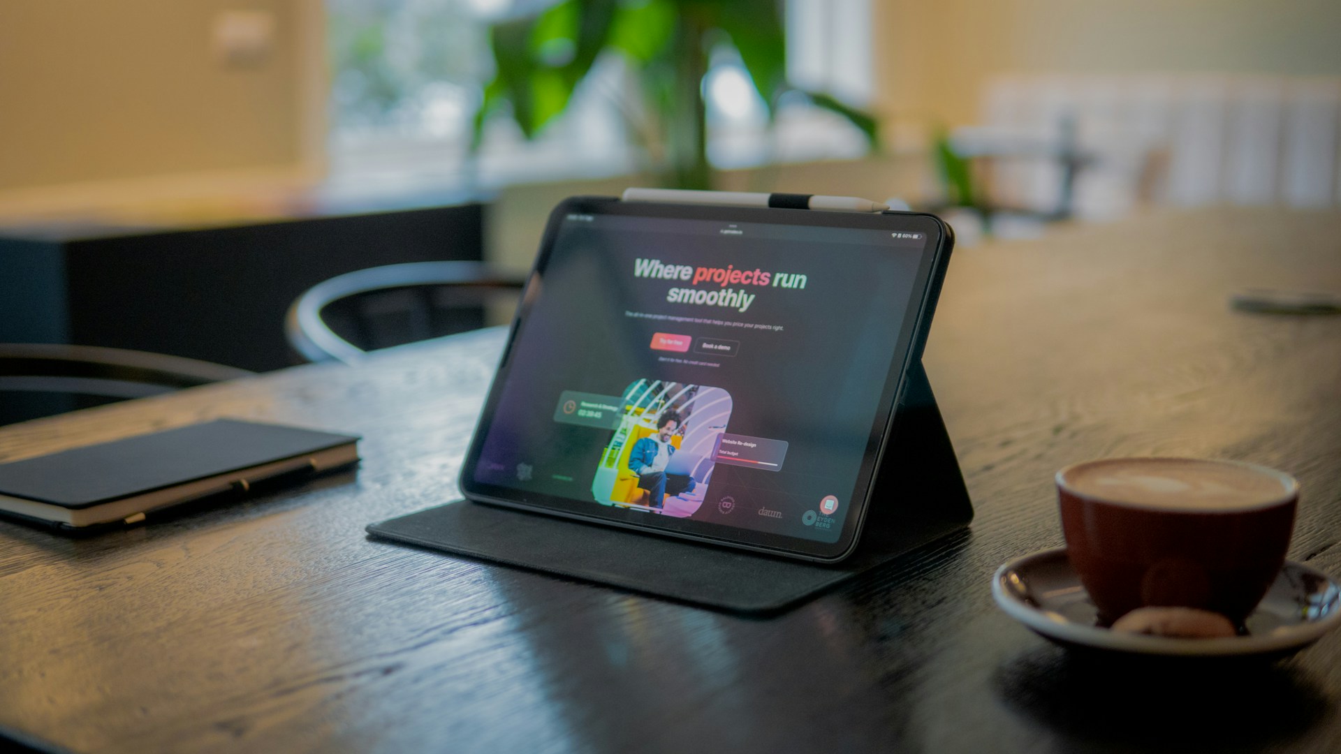 a tablet sitting on top of a wooden table next to a cup of coffee