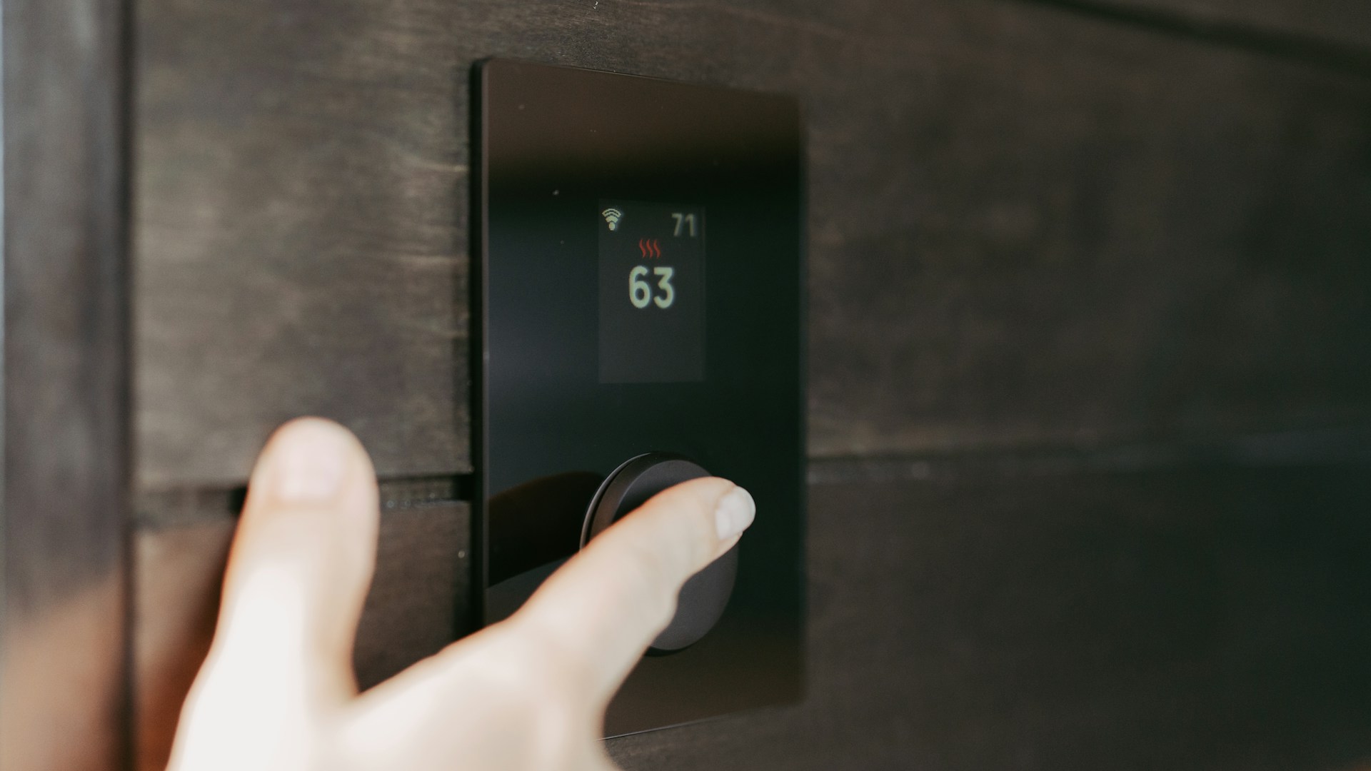 Hand adjusting a digital thermostat display