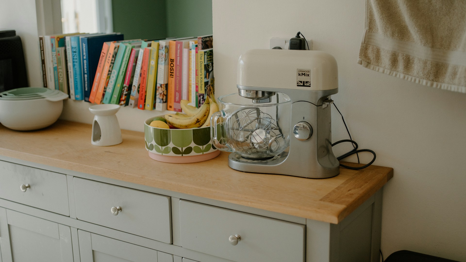 Kitchen counter with mixer, fruit bowl, and books.